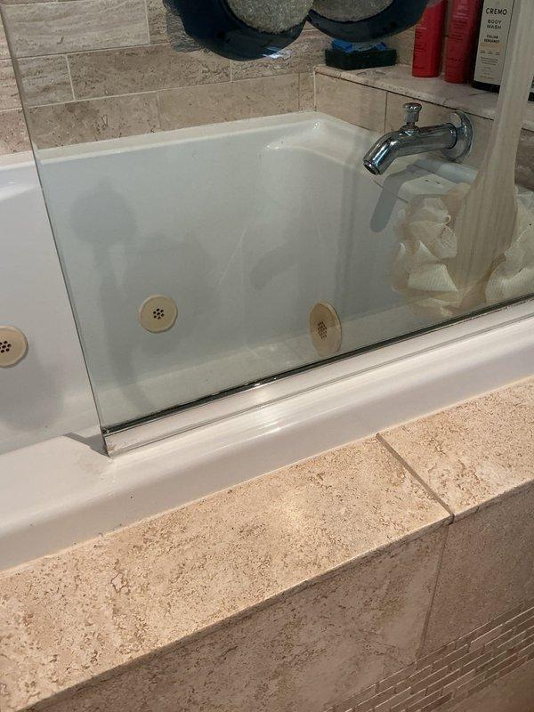 Responded to service call for shower drain leak causing water damage to ceiling below. Upon arrival, inspected bathroom with travertine tile surround and fiberglass tub enclosure. Examined shower drain assembly and surrounding areas for signs of water intrusion. Identified compromised drain seal allowing water to bypass drain connection and penetrate subfloor. Removed drain cover and tested drain line for proper flow and blockages. Disassembled drain assembly to access weep holes and gasket. Found deteriorated rubber gasket and improper seal at drain body connection. Cleaned drain opening and removed old plumber's putty and debris. Installed new drain gasket and reassembled drain assembly with proper sealant application. Torqued drain body to manufacturer specifications ensuring watertight seal. Conducted water flow test by running shower at full pressure for extended period while monitoring ceiling below for any signs of moisture penetration. Verified no active leaking present. Docume
