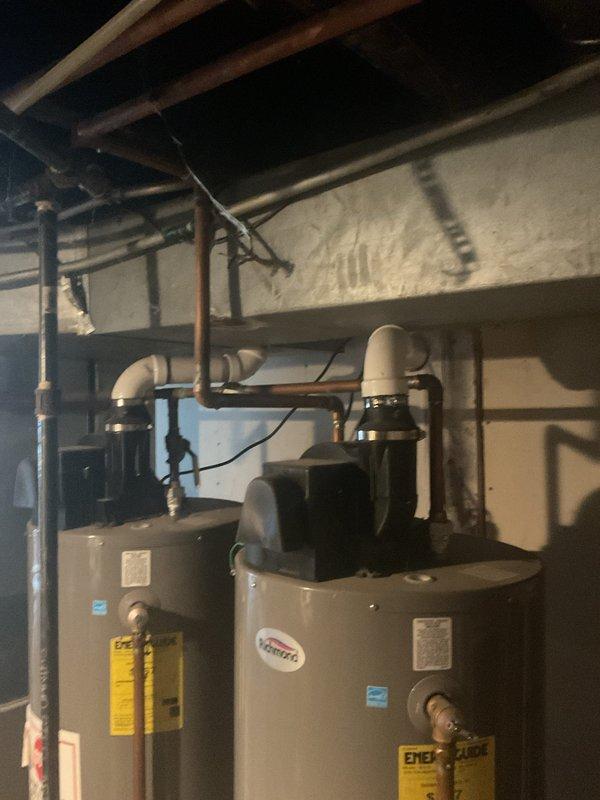Responded to service call for tanked water heater with reported small leak potentially originating from bottom of unit. Upon inspection, assessed dual water heater installation in basement utility area, examining both Richmond-branded units, associated copper and PVC plumbing connections, and valve assemblies for signs of moisture or active leaking. Documented equipment condition through photography for service records and further evaluation of leak source.