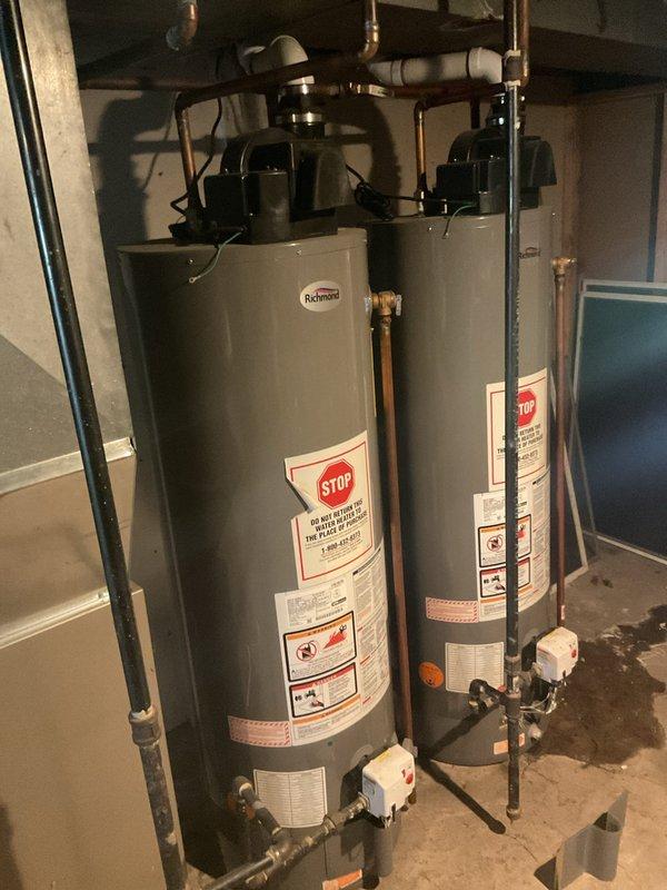 Responded to service call for tanked water heater with reported small leak potentially originating from bottom of unit. Upon inspection, assessed dual water heater installation in basement utility area, examining both Richmond-branded units, associated copper and PVC plumbing connections, and valve assemblies for signs of moisture or active leaking. Documented equipment condition through photography for service records and further evaluation of leak source.