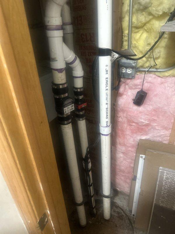 Responded to service call for sump pump replacement in basement utility area. Upon arrival, contacted tenant as requested and assessed existing sump pit system with battery backup. Inspected current installation including PVC discharge piping (Schedule 40), check valve assembly, and electrical connections. Documented existing plumbing configuration showing vertical discharge lines secured with mounting brackets, green metal support structure, and multiple PVC connections with rubber couplings. Noted moisture staining on concrete floor around pit area indicating previous water activity. Photographed complete system setup including pipe routing through unfinished space with visible insulation and electrical junction box. Prepared detailed estimate for pit sump pump and battery backup replacement, documenting all necessary components and labor requirements for owner approval before proceeding with installation work.