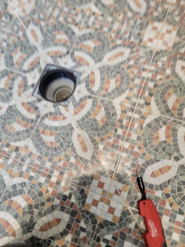 Responded to slow-draining bathroom sink and floor drain. Cleared blockage from drain lines using professional drain cleaning equipment, restoring proper water flow to both the undermount sink with its pop-up drain assembly and the decorative mosaic tile floor drain. Both fixtures now draining at normal speed with no standing water remaining.