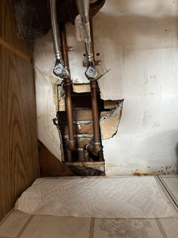 Responded to water leak under kitchen sink originating from supply valve area. Upon inspection, identified failed connection at braided stainless steel supply line fitting installed during previous re-pipe work approximately 2-3 years prior. Shut off water supply and removed defective flexible supply lines with brass fittings. Inspected copper stub-out connections and cabinet interior for additional water damage or deterioration. Replaced both hot and cold water braided supply lines with new assemblies, ensuring proper gasket seating and torque specifications on threaded connections. Tested system under full pressure, verified no leaks at valve connections or fittings, and confirmed proper water flow to fixtures.