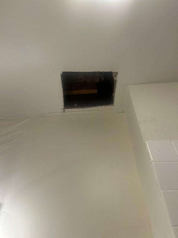 Responded to urgent water leak affecting multiple units. Investigated reported leak originating from bathtub area with potential roof involvement. Accessed ceiling cavity through existing opening to inspect plumbing lines and structural components for source of water intrusion. Identified leak pathway and assessed damage to surrounding drywall and neighboring unit below. Documented conditions with photos of bathroom vanity area and ceiling access point showing water damage patterns and structural elements. Isolated leak source and performed necessary repairs to stop active water flow and prevent further damage to adjacent property.