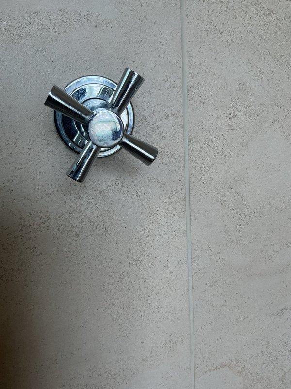 Responded to callback regarding ongoing noise issue reported since previous service visit. Conducted thorough inspection of shower valve assembly and trim components to identify source of sound captured on customer-provided video. Examined chrome-plated dual-control shower valve system, escutcheon plate, and cartridge mechanisms for loose components, water hammer, or mechanical vibration. Documented existing shower fixture condition with photographs showing cross-handle trim and valve assembly mounted on tiled wall for service records and further diagnostic evaluation.
