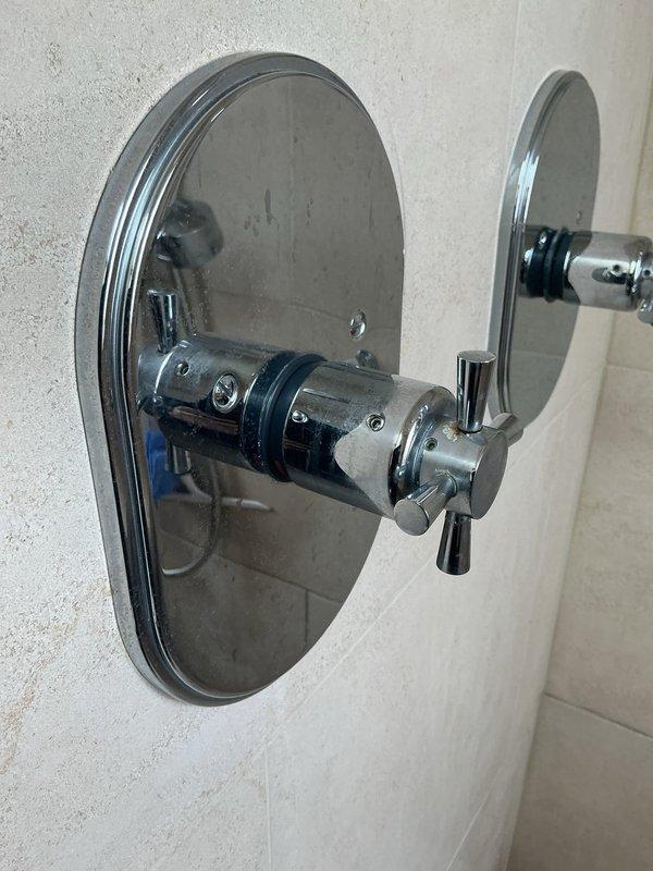 Responded to callback regarding ongoing noise issue reported since previous service visit. Conducted thorough inspection of shower valve assembly and trim components to identify source of sound captured on customer-provided video. Examined chrome-plated dual-control shower valve system, escutcheon plate, and cartridge mechanisms for loose components, water hammer, or mechanical vibration. Documented existing shower fixture condition with photographs showing cross-handle trim and valve assembly mounted on tiled wall for service records and further diagnostic evaluation.