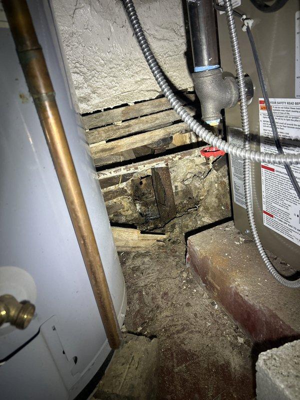 Completed kitchen drain line re-pipe due to severely corroded underground tie-in to main sewer stack. Removed section of wall behind existing drain to expose plumbing, cut into kitchen stack with new PVC fittings, and rerouted new drain line from kitchen sink to 4-inch main stack. Installed new tubular drain assembly under sink with PVC wye fittings to provide clean out access, secured exposed drain line to wall using J hooks for proper pitch, capped failed kitchen line with Hydro cement, and sealed ground penetration hole with stone and concrete fill.