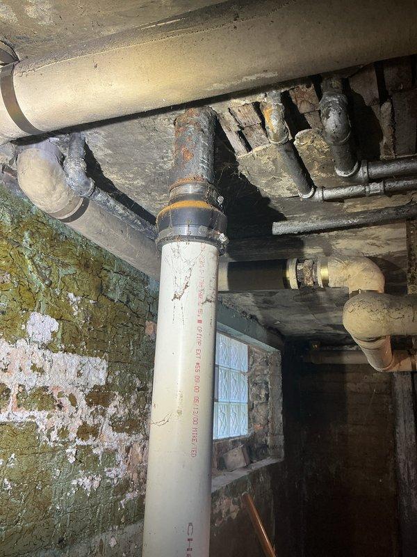 Responded to plumbing issue involving cast iron main stack connection to kitchen sink drain. Accessed work area by removing drywall section to expose wall cavity and plumbing infrastructure. Replaced deteriorated cast iron stack connection with new PVC drainage system, including vertical drain pipes and multiple elbow fittings to properly route kitchen sink drain to main stack. Secured all new plumbing components with appropriate hangers and supports to ceiling joists. Verified proper drainage flow and leak-free connections throughout modified system.
