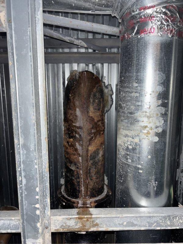 Responded to reported ceiling leak and conducted annual tanked water heater maintenance inspection. Upon arrival, accessed fourth-floor unit via elevator and performed comprehensive visual assessment of plumbing systems. Inspected under-sink plumbing, confirming P-trap and drain connections were secure with no active leaks detected at cabinet fixtures. Examined water heater system and identified severe corrosion on left vertical pipe with heavy rust buildup and deterioration, while adjacent pipe showed moisture condensation with mineral deposit streaking. Documented conditions with photographs for records. Water heater operational but left pipe corrosion presents concern for future integrity. No immediate leaks found at time of inspection; recommended monitoring corroded components for potential replacement to prevent future failure.