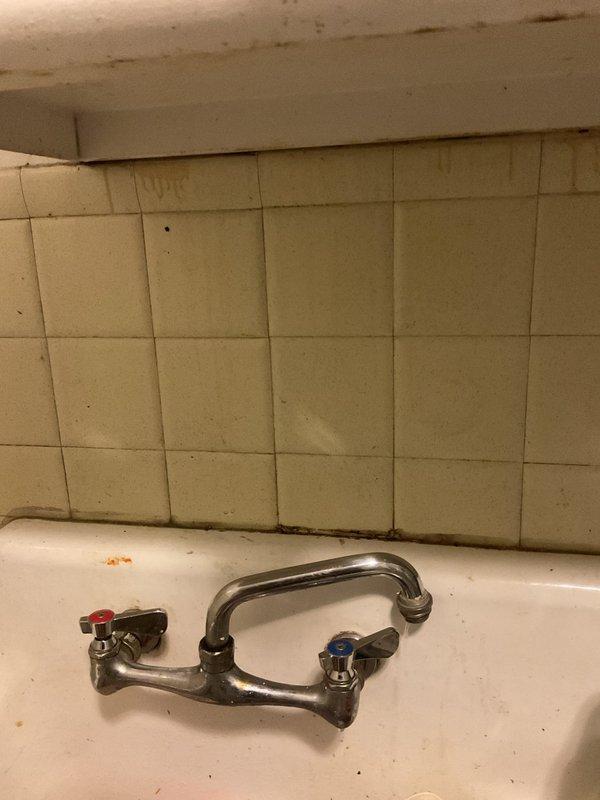 Responded to emergency call for kitchen sink actively leaking due to complete rust-through failure of drain assembly. Upon arrival, found severely corroded P-trap and drain piping with extensive deterioration causing uncontrolled water discharge. Existing drain system showed advanced age with significant rust penetration compromising pipe integrity. Shut off water supply and removed failed rusted drain components including P-trap assembly and connecting tailpiece. Installed new chrome-plated drain assembly with properly sized P-trap, ensuring proper slope and secure wall mounting. Tested system for leaks under full water flow and verified proper drainage function. Cleaned work area and disposed of corroded materials.