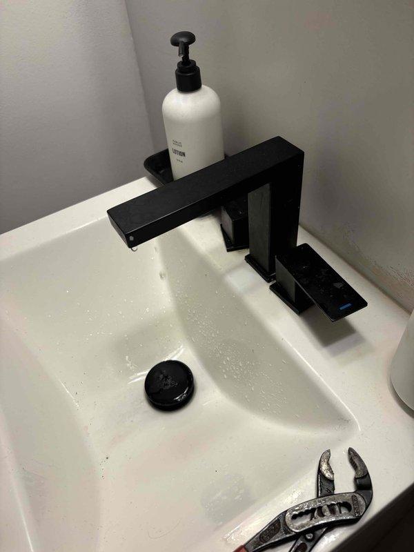 Responded to low water pressure complaint at residential bathroom sink. Upon inspection, identified clogged faucet aerator as the source of reduced flow. Removed aerator assembly from waterfall-style black matte faucet using adjustable wrench. Disassembled aerator components, including mesh screen and retaining ring, which showed significant sediment and mineral buildup restricting water flow. Cleaned all aerator parts thoroughly, reassembled components, and reinstalled onto faucet. Tested water pressure after service and confirmed restoration to normal flow rate.