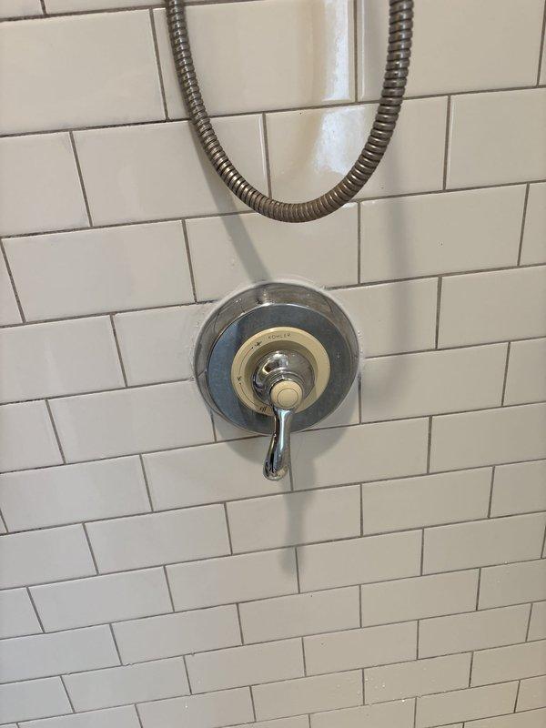 Responded to warranty callback for recently installed shower valve experiencing leaking and temperature control issues. Upon arrival, inspected chrome shower valve assembly with handheld showerhead system mounted on white subway tile wall. Customer reported valve was only delivering hot water and had developed a leak following initial installation. Diagnosed faulty cartridge installation in single-lever mixing valve. Removed escutcheon plate and accessed valve body to inspect cartridge seating and orientation. Corrected cartridge positioning to restore proper hot/cold water mixing function. Tested temperature control through full range of motion to verify balanced water delivery. Addressed leak source at valve connection points, tightened compression fittings, and verified all seals were properly seated. Cycled valve multiple times to confirm leak resolution and proper temperature regulation from cold to hot settings. System now operating within manufacturer specifications with no acti