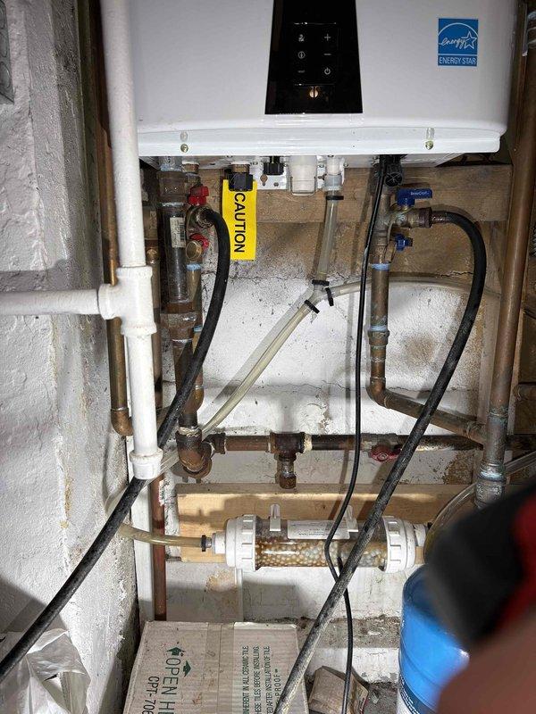 Completed VIP maintenance service on tankless water heater system. Performed descaling flush procedure using citric acid solution circulated through the unit's heat exchanger to remove mineral buildup and scale deposits. Connected flush pump and hoses to service valves, allowing cleaning solution to cycle through the system for proper maintenance intervals. Inspected all plumbing connections, including copper supply lines, flexible hoses, PVC venting, and ball valve shutoffs for proper operation and signs of wear. Verified water filter condition and sediment trap functionality. Confirmed unit operational status and proper temperature control settings upon completion of maintenance procedures.