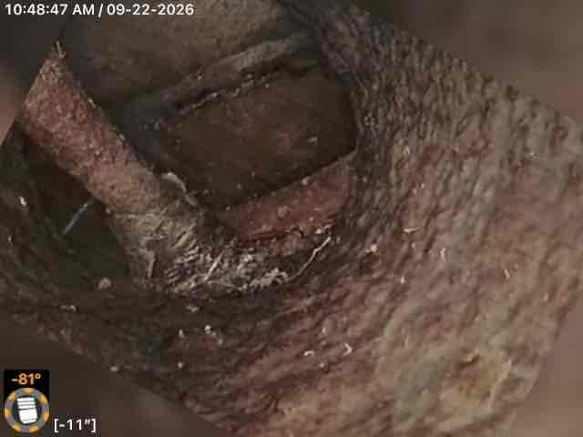 Conducted inspection of interior ductwork system revealing extensive corrosion and deterioration throughout metal piping, with significant rust buildup, flaking surfaces, and mineral deposits indicating prolonged moisture exposure. Documented site conditions including exterior access points and surrounding property layout for future service planning.