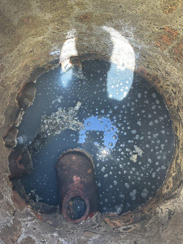 Completed follow-up visit to collect down payment for previously sold sewer cleanout cover replacement repair. Documented existing weathered circular metal access cover with perforated surface and corroded lifting mechanism set in concrete pad within flagstone patio area, confirming scope of work for upcoming installation.