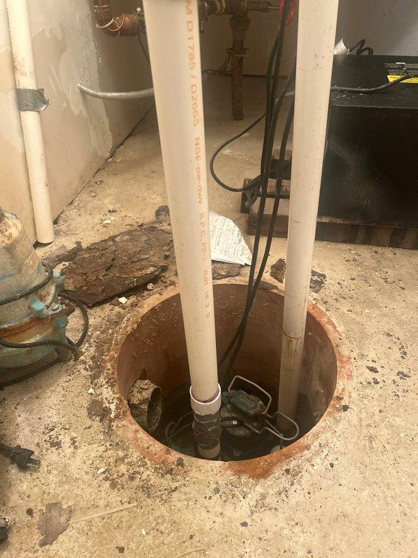 Completed comprehensive assessment of existing dual sump pump system showing extensive deterioration and operational concerns. Both pumps exhibited severe corrosion, rust damage, and paint degradation consistent with prolonged moisture exposure and age-related failure. The primary pump displayed heavy rust throughout the casing and metal components, while the secondary backup pump showed significant paint flaking and corrosion spots. Evaluated the sump pit configuration, which contained standing water and deteriorated concrete surfaces with substantial sediment accumulation. Inspected white PVC discharge piping assembly including check valve and backflow preventer connections. Documented floor staining, debris buildup, and wall discoloration indicating chronic moisture issues and inadequate drainage management. Provided detailed estimate for complete sump pump system replacement including removal of both failed units, pit cleaning, installation of new primary and backup pump units with
