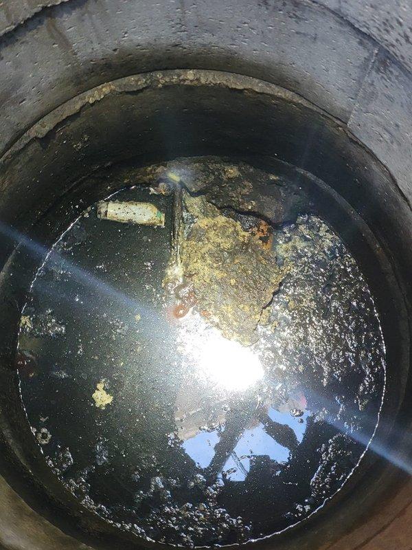 Responded to service request for catch basin pumping. Upon arrival, found catch basin containing dark, stagnant water with significant accumulation of organic debris and sediment floating on the surface. The concrete structure showed signs of age with mineral deposits and staining along interior walls. Successfully pumped and cleaned catch basin, removing accumulated sludge, organic material, and standing water from the system. Documented pre-service conditions showing heavy sediment buildup and contaminated water. Catch basin restored to proper working condition and left clear of obstructions to ensure proper drainage function.