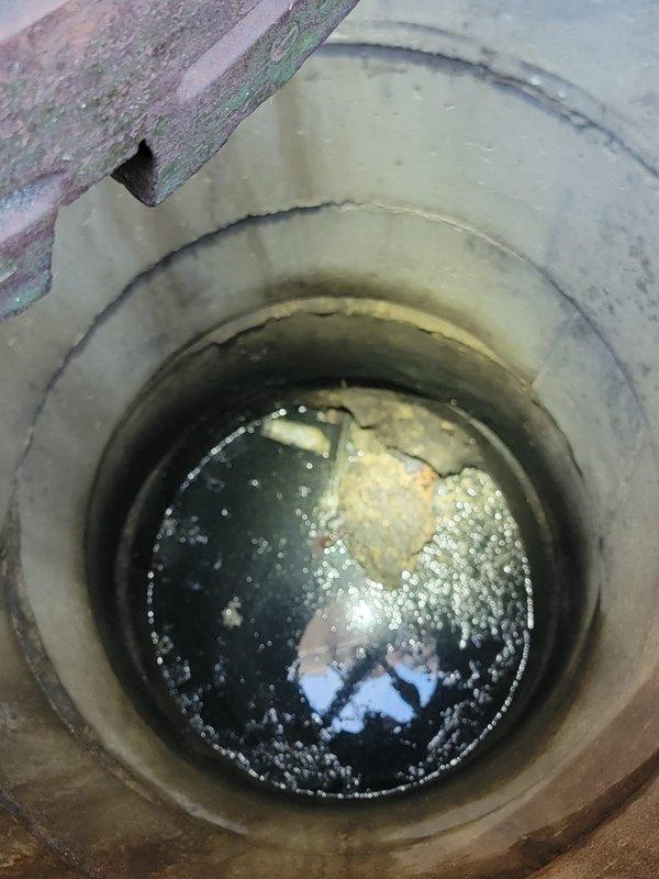 Responded to service request for catch basin pumping. Upon arrival, found catch basin containing dark, stagnant water with significant accumulation of organic debris and sediment floating on the surface. The concrete structure showed signs of age with mineral deposits and staining along interior walls. Successfully pumped and cleaned catch basin, removing accumulated sludge, organic material, and standing water from the system. Documented pre-service conditions showing heavy sediment buildup and contaminated water. Catch basin restored to proper working condition and left clear of obstructions to ensure proper drainage function.