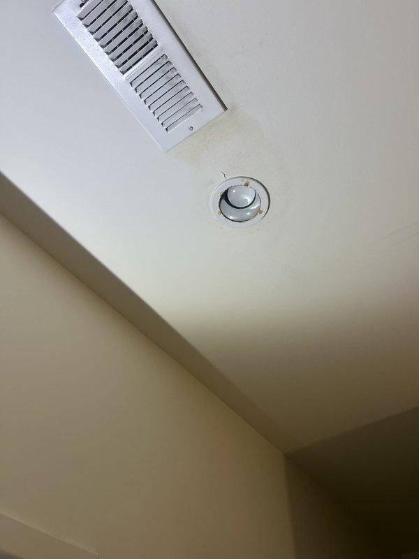 Responded to water leak investigation originating from rooftop and affecting restaurant ceiling below. Upon arrival, inspected interior ceiling damage showing water intrusion near HVAC register vent and recessed lighting fixture. Documented moisture staining and discoloration on white ceiling surface indicating active leak path from above. Traced water migration pattern through ceiling assembly to determine source location. Also inspected upper-level bathroom shower enclosure with multi-head shower system as potential contributing source, examining all wall-mounted fixtures, body spray jets, valve assemblies, and tile waterproofing integrity for signs of water penetration behind wall surfaces.