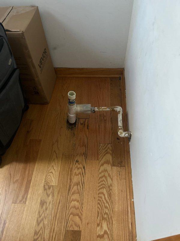 Installed gas line plumbing for dryer connection and completed drain plumbing infrastructure for washer appliance. Work included installation of dual shut-off valves with manual wheel handles in recessed wall access box, along with white PVC drain line configuration featuring 90-degree elbows and cleanout access point positioned at floor level in corner installation.