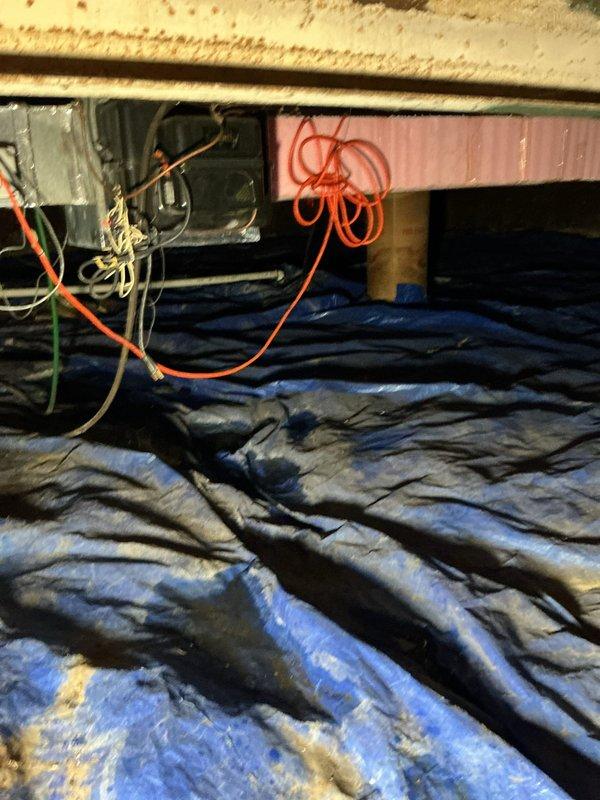 Inspected crawl space to investigate reported leaking from outdoor spigot that had been recently replaced but was surrounded by concrete. Accessed underfloor area and examined plumbing infrastructure, vapor barrier integrity, and foundation walls for signs of water intrusion. Documented existing conditions including PVC piping, insulation, electrical wiring, and moisture indicators on foundation surfaces to assess potential leak source and water damage.