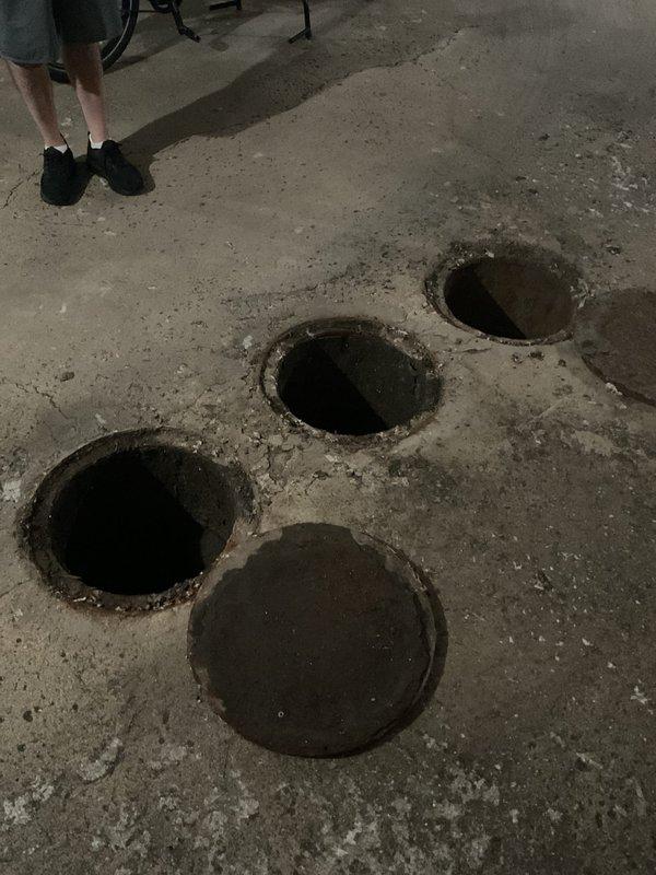 Responded to service call for catch basin maintenance and inspection. Upon arrival, accessed multiple catch basin openings in concrete floor to assess drainage system condition. Removed covers from several catch basins to inspect for blockages and debris accumulation that could be causing backup issues. Performed thorough cleaning of catch basins, removing sediment, debris, and buildup from basin interiors. Inspected connecting pipes and drainage lines for obstructions or flow restrictions. Documented pre-service and post-service conditions with photographs showing basin locations and access points. All catch basins cleaned and verified for proper drainage function before replacing covers and completing service.