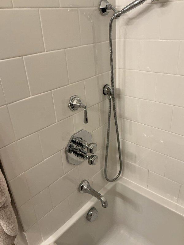 Responded to no hot water issue at bathtub fixture. Upon inspection, found chrome dual-handle thermostatic shower valve with handles potentially over-tightened, restricting hot water flow. Adjusted valve handles to proper operating position, restoring full hot water delivery to tub spout and shower fixtures.