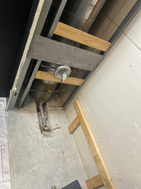 Conducted site assessment of existing plumbing infrastructure in unfinished space with exposed ceiling structure and corroded overhead fixture. Documented conditions of aged mechanical components and HVAC ductwork for preparation of piping estimate, with photos taken for detailed proposal development.
