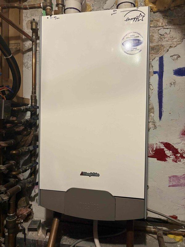 Completed installation and configuration of wall-mounted tankless water heater system in basement mechanical room. Installed comprehensive copper and PVC piping network with manifold system, brass valves, and multiple branch connections to integrate new tankless unit with existing traditional storage water heater. Configured dual heating system with proper venting, pressure relief components, and shutoff valves to ensure safe and efficient operation of both heating appliances working in conjunction.