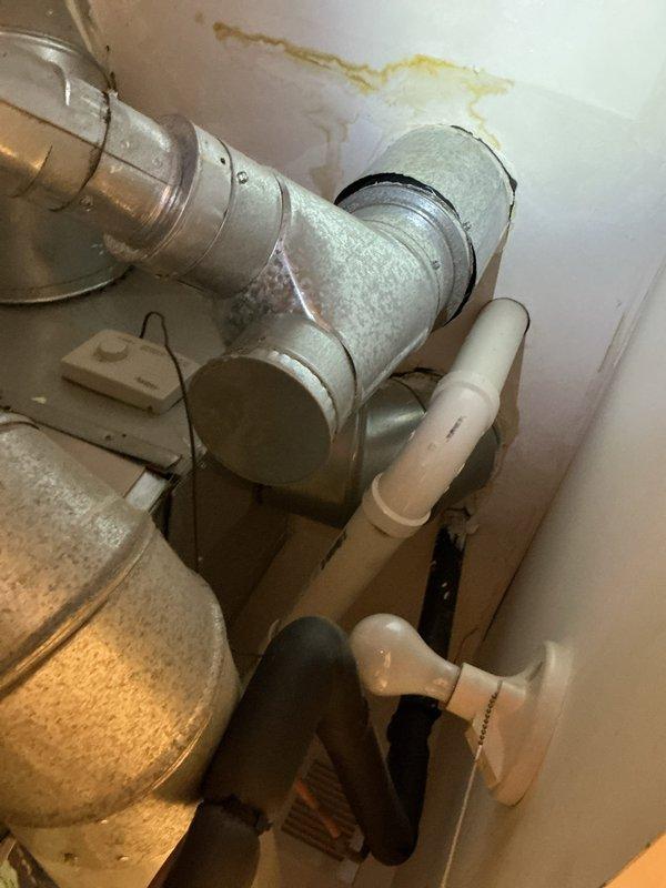 Responded to ceiling leak complaint and conducted thorough inspection of plumbing system. Upon investigation, identified active water leak originating from deteriorated P-trap assembly beneath bathroom vanity. Observed significant water staining on wall surfaces above piping, indicating prolonged moisture intrusion that had migrated upward through ceiling cavity. Documented existing conditions including mineral buildup on drain pipes, corrosion on metal trap components, and water damage to surrounding drywall. Photographed affected areas for service records and recommended immediate replacement of compromised trap assembly to prevent further water damage and potential mold development.