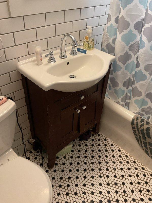 Responded to service call for reported water leak adjacent to toilet. Upon inspection, examined the vanity cabinet beneath the sink and surrounding bathroom fixtures including toilet base, flooring, and plumbing connections. Investigated potential sources of moisture in the area, checking supply lines, drain connections, and wax ring seal at toilet base. Documented conditions of penny tile flooring and areas around plumbing fixtures for moisture presence. No active leak was observed during inspection period, though continued monitoring was recommended if moisture concerns persist.