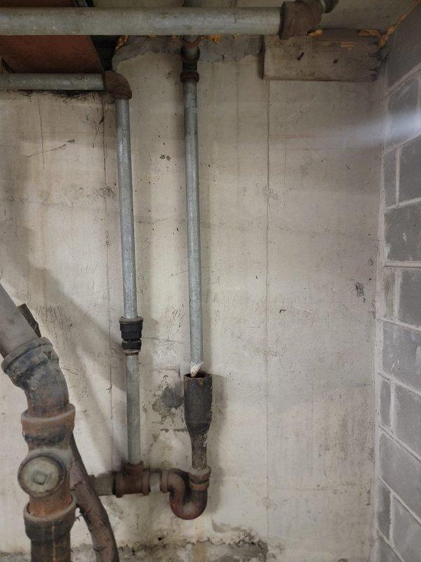Responded to a blocked condensate drain call and performed inspection of the plumbing system. Upon arrival, located the condensate drain line in the basement utility area and identified blockage preventing proper drainage. Cleared the obstruction from the condensate line using appropriate tools and verified proper flow was restored. Inspected surrounding plumbing infrastructure during service, noting significant rust and corrosion present on older metal piping components including vertical drain pipes and trap assemblies, though these were not affecting current system operation. Condensate drain is now flowing freely and functioning as designed.