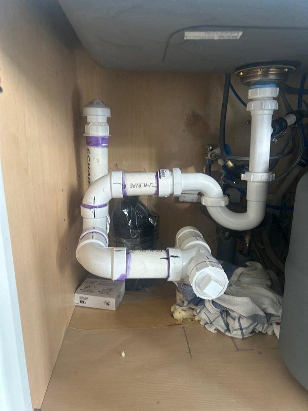 Completed under-sink plumbing repair involving replacement and reconfiguration of PVC drain assembly including P-trap and associated fittings beneath kitchen sink. Additionally performed copper pipe repairs and modifications in basement utility area, addressing water supply lines and ensuring proper connections and support throughout the plumbing system.