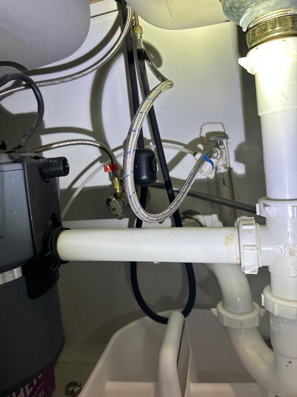 Responded to report of leak underneath kitchen sink. Upon inspection, identified source of leak at kitchen faucet supply line connection. Examined all plumbing components under sink including PVC drain assembly, P-trap, flexible braided supply lines, and garbage disposal unit. Tightened loose compression fittings on braided stainless steel water supply line and verified all drain connections were secure. Tested faucet operation and checked for additional leaks throughout system. All connections now secure with no active leaks detected.