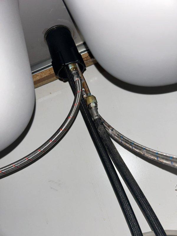 Responded to report of leak underneath kitchen sink. Upon inspection, identified source of leak at kitchen faucet supply line connection. Examined all plumbing components under sink including PVC drain assembly, P-trap, flexible braided supply lines, and garbage disposal unit. Tightened loose compression fittings on braided stainless steel water supply line and verified all drain connections were secure. Tested faucet operation and checked for additional leaks throughout system. All connections now secure with no active leaks detected.