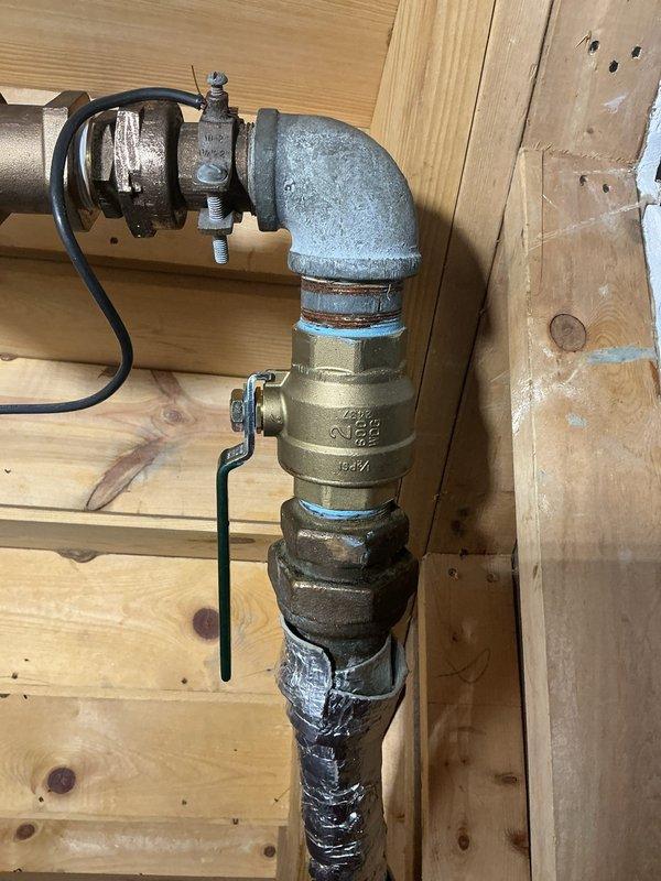 Replaced main water valve assembly on building water supply line. Shut off water supply to building using Buffalo Key prior to valve replacement. Removed old brass valve showing signs of age and mineral deposits, then installed new valve assembly with proper fittings connecting galvanized and copper pipe sections. Verified all connections were secure and tested system for proper operation and leaks upon water restoration.