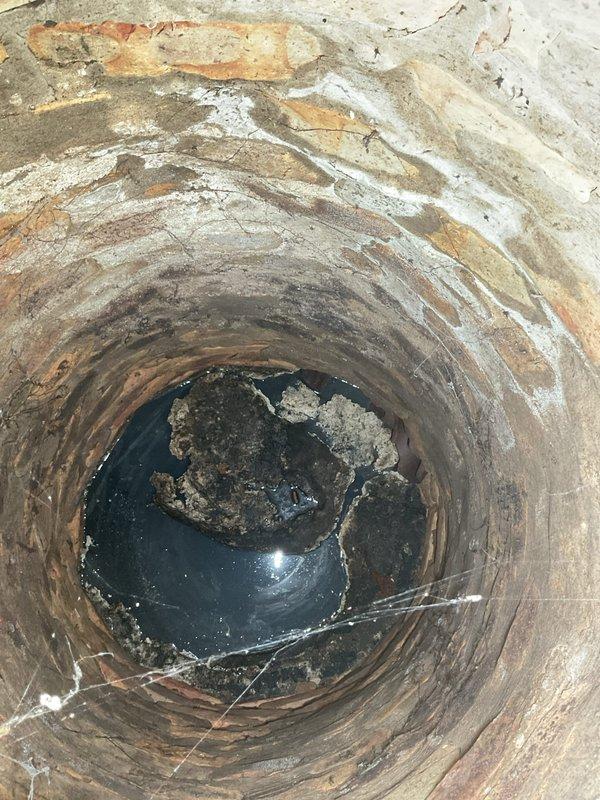 Responded to service call for water backing up through basement floor drain. Upon inspection, found catch basin with significant deterioration, rust, and corrosion throughout interior walls, with standing water and debris accumulation at bottom. Documented existing conditions and provided estimate for catch basin cleaning services to address drainage issue and prevent further basement water infiltration.