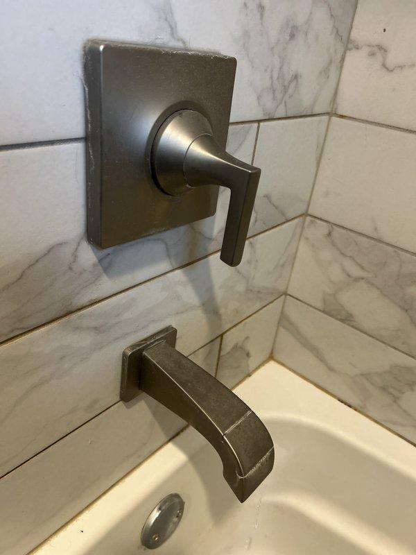 Responded to service call for continuously leaking bathtub faucet. Upon inspection, identified issue with wall-mounted tub spout and single-handle control valve assembly in bronze finish. Accessed shut-off valve behind square escutcheon plate, replaced faulty internal cartridge components, and tested for proper water flow and complete shut-off. Leak successfully resolved, fixture restored to normal operation.
