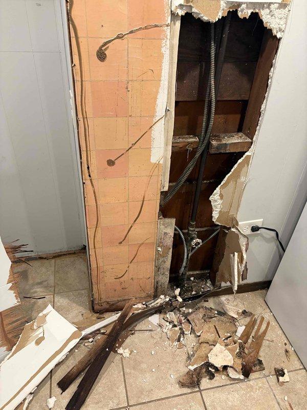 Responded to service call and provided morning ETA communication. Upon arrival, assessed significant water damage that required emergency demolition of interior drywall to access affected plumbing infrastructure. Removed damaged wall sections exposing wooden studs and plumbing lines in bathroom-adjacent area. Documented extensive demolition debris and exposed piping system. Inspected basement mechanical room containing complex network of heating and domestic water systems, including water heater, expansion tank, circulator pumps, and associated piping with multiple valves and gauges. Presented repair options and successfully sold comprehensive plumbing repair scope to address water damage and underlying system issues.