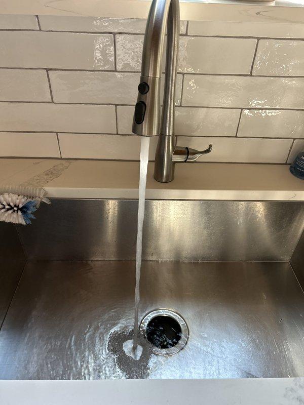 Completed plumbing repair service involving bathroom sink P-trap assembly and kitchen faucet installation. Tightened and secured chrome P-trap connections beneath bathroom vanity using adjustable wrench to ensure proper drainage and eliminate leaks. Installed pull-down kitchen faucet with brushed nickel finish and verified water flow functionality, confirming proper operation and no leaks at connection points.