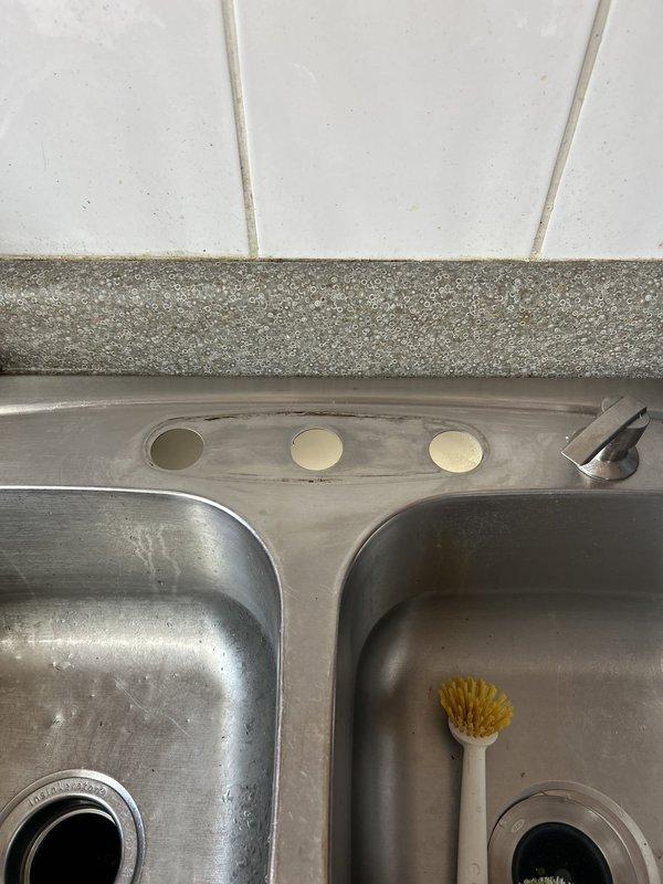 Completed installation of new brushed stainless steel kitchen faucet with pull-down spray head on existing double-basin sink. Mounted faucet assembly through center deck holes, connected hot and cold water supply lines, installed soap dispenser accessory, and tested all functions to ensure proper operation and no leaks.