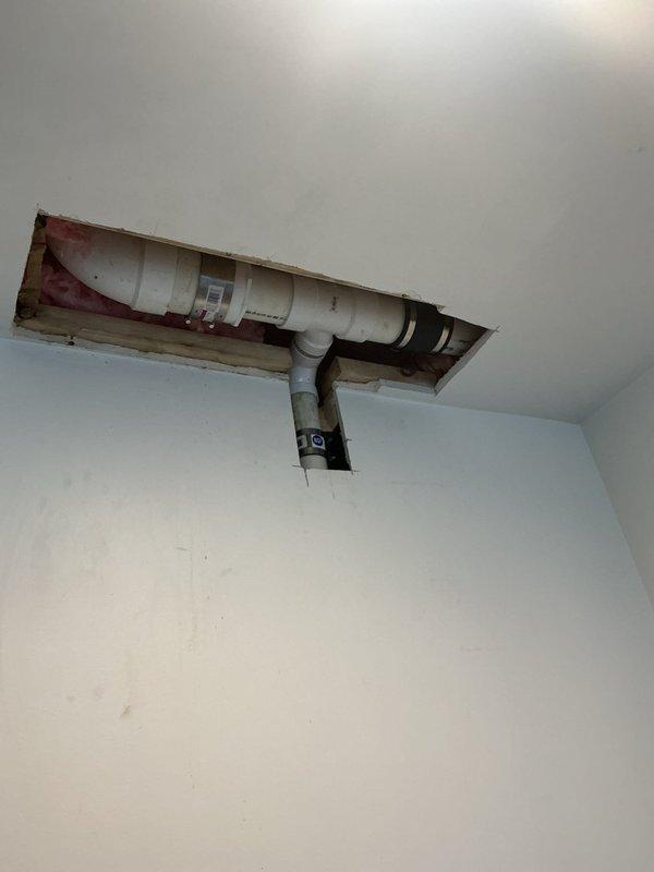 Completed plumbing repair involving ceiling access to drainage system. Created access openings in ceiling to expose PVC drain and vent piping for inspection and repair work. Addressed plumbing issues with horizontal drain line and vertical vent stack, including work on elbow joint connections. Ceiling panels were removed to provide necessary access to wooden framing and plumbing infrastructure above.