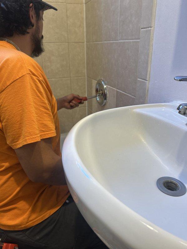 Completed plumbing repair involving access and replacement of shower valve assembly. Cut access opening in adjacent wall to reach plumbing system behind shower, exposing vertical copper supply lines and valve body. Removed and replaced malfunctioning shower valve control with new chrome fixture, ensuring proper connection to existing copper piping. Tested water flow and temperature control operation to verify proper function before completing work.