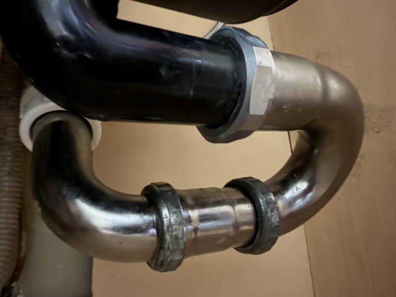 Conducted follow-up assessment of under-sink plumbing configuration to evaluate installation requirements for new water filtration system while maintaining existing garbage disposal. Inspected current P-trap assembly, PVC drain connections, and available cabinet space to determine optimal placement of filtration unit and verify compatibility with disposal drain line. Reviewed existing 45-degree drain fitting and discussed potential modification to 90-degree configuration if disposal removal becomes necessary, providing recommendations for proper drainage solutions that accommodate both the new filtration system and existing waste disposal setup.