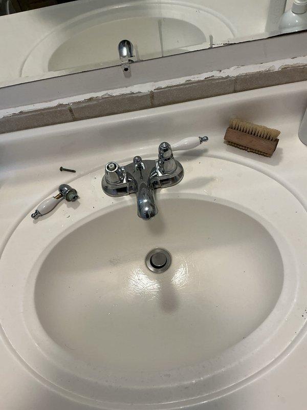 Replaced existing chrome bathroom sink faucet with new fixture, including removal of old two-handle assembly and installation of updated faucet with proper supply line connections. Verified all connections under sink were secure and leak-free, tested hot and cold water flow through both handles, and confirmed proper drainage operation.
