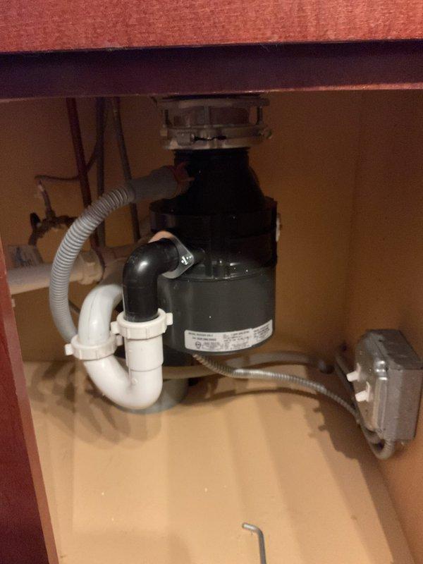 Responded to service call for non-operational garbage disposal unit at kitchen sink. Upon inspection, found the disposal unit had lost power due to a tripped reset button on the bottom of the unit. Verified electrical connection at wall outlet was secure and functioning properly. Pressed the red reset button on the disposal base to restore power. Tested unit operation with cold water running to confirm proper function and verify no unusual sounds, vibrations, or leaks. Inspected mounting assembly, drain connections, and dishwasher drain line for any signs of damage or deterioration—all components found to be in good condition. Checked P-trap configuration and verified proper drainage. Unit restored to full working order.