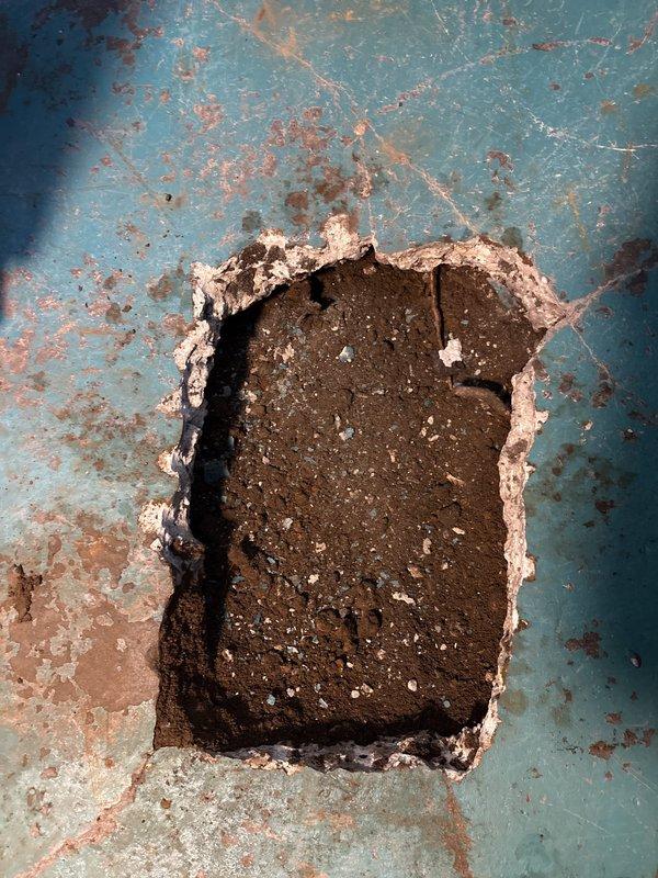 Completed plumbing repair assessment and documentation of severely deteriorated floor drain assembly and surrounding concrete surface. The existing drain cover and frame showed extensive corrosion with complete paint system failure, exposing rust-damaged metal substrate throughout. Removed failed drain cover assembly from rectangular opening, revealing deteriorated sealant and adhesive materials around perimeter. Documented heavy moisture damage to concrete floor surface with significant coating delamination, exposing underlying substrate in multiple areas. Rust staining patterns indicated chronic water exposure and drainage issues. Photographed existing conditions to support recommended replacement of drain assembly and floor surface restoration in affected areas.