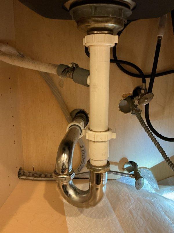 Replaced existing garbage disposal unit with new blue model, including complete reinstallation of mounting assembly and drain connections. Addressed corroded brass fitting at P-trap connection by installing new white PVC components to ensure proper drainage and eliminate potential leak points. Verified all connections are secure, tested disposal operation, and confirmed no leaks present throughout the drain system.