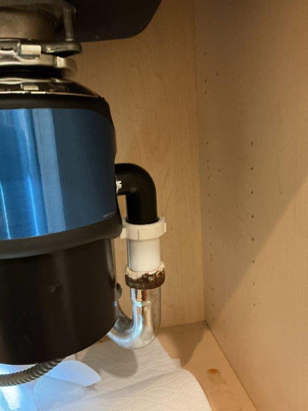 Replaced existing garbage disposal unit with new blue model, including complete reinstallation of mounting assembly and drain connections. Addressed corroded brass fitting at P-trap connection by installing new white PVC components to ensure proper drainage and eliminate potential leak points. Verified all connections are secure, tested disposal operation, and confirmed no leaks present throughout the drain system.