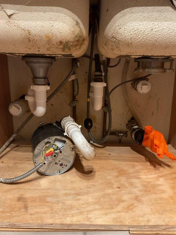 Responded to a persistent kitchen sink drainage issue that began following grease trap removal and garbage disposal replacement. Upon arrival, found double-basin sink with newly installed disposal unit that remained non-functional despite previous 30-foot cable rodding attempts by another contractor. Inspected under-sink plumbing configuration including PVC P-traps, drain assemblies, and disposal connections. Identified blockage or improper drainage pathway downstream of disposal unit that was not resolved by standard augering methods. Cleared obstruction and restored proper drainage flow to both sink basins. Tested system operation with disposal running and water flowing through both basins to verify complete resolution. Photographed completed plumbing configuration showing proper P-trap installation, disposal connections, and supply line routing for service documentation.