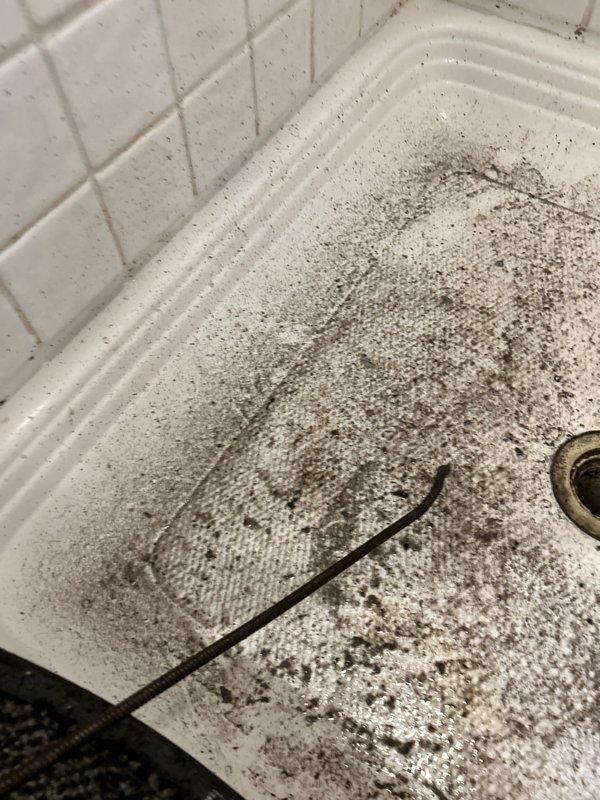 Responded to complaint of water backing up in standing shower with visible debris. Upon arrival, found shower drain experiencing significant blockage with debris accumulation visible in both the shower pan and connected fixtures. Cleared obstruction from shower drain line using appropriate drain cleaning equipment. Removed accumulated debris and sediment that had caused the backup condition. Tested drainage flow to confirm proper operation and verified water now drains freely without backup. System restored to normal function.
